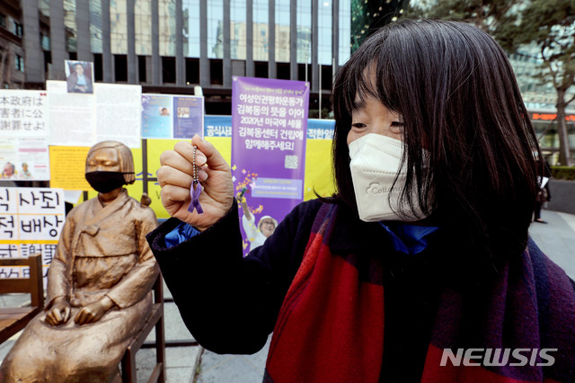 [서울=뉴시스]김병문 기자 = 윤미향 전 정의기억연대 이사장이 8일 오후 서울 종로구 옛 일본대사관 앞에서 온라인으로 열린 일본군 성노예제 문제해결을 위한 제1434차 정기수요시위에 참석해 보라색 리본 배지를 들어보이고 있다. 2020.04.08.  dadazon@newsis.com 