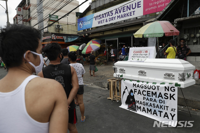 [마닐라=AP/뉴시스]9일(현지시간) 필리핀 마닐라의 한 시장 외부에 "마스크 쓰면 코로나19에 걸리지도 않고 죽지도 않으리"라고 쓰인 현수막과 함께 빈 관이 진열돼 있다. 필리핀의 코로나19 확진자 수는 8일 기준 3660명이고 사망자 수는 163명으로 집계됐다. 2020.04.09.