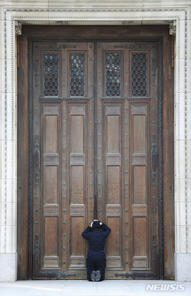 [런던=AP/뉴시스] 영국 성공회가 부활절에도 코로나 19로 인한 회당 폐쇄 조치를 이어간 가운데 12일 한 신도가 본당인 런던 웨스트민스터 성당 문 앞에 무릎 꿇고 기도하고 있다 2020. 4. 12. 