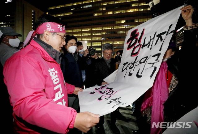 [서울=뉴시스]김병문 기자 = 제21대 국회의원 선거 종로구에 출마한 황교안 미래통합당 후보가 선거유세 마지막날인 14일 오후 서울 종로구 광화문광장 이순신 장군 동상 앞에서 선거 마무리 대국민 호소를 마친 후 지지자가 든 응원 문구를 읽고 있다. 2020.04.14. dadazon@newsis.com