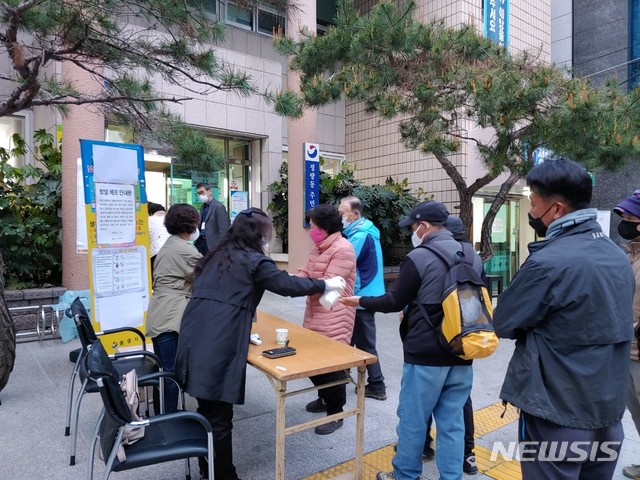 [통영=뉴시스]신정철 기자= 21대 총선 경남 통영시·고성군 국회의원 선거구 투표가 15일 오전 6시부터 총 73개 투표소에서 순조롭게 개시됐다. 이날 통영시 정량동주민센터에 마련된 정량1투표소 입구에는 오전 6시께 유권자들이 마스크를 착용하고 1m 거리두기를 하면서 손소독과 발열검사를 받고 있다. 2020.04.15.  sin@newsis.com 