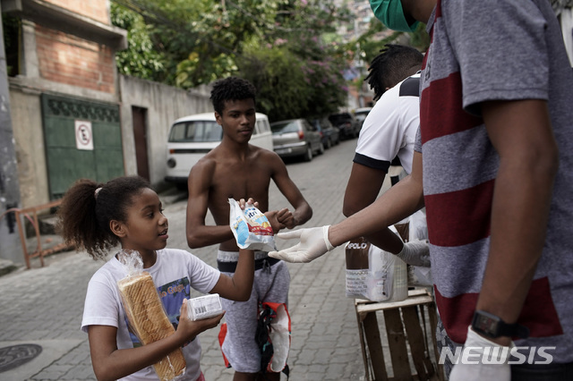 [리우데자네이루=AP/뉴시스]15일(현지시간) 브라질 리우데자네이루의 한 문화센터에서 한 소녀가 무료 음식을 받고 있다. 브라질에서 신종 코로나바이러스 감염증(코로나19)의 가장 큰 피해 지역인 상파울루와 리우데자네이루 주지사들은 코로나19의 확산을 막기 위해 공개 집회를 금지하고 학교와 사업장 등을 폐쇄했으며 엄격한 사회적 거리 두기를 요구했다. 