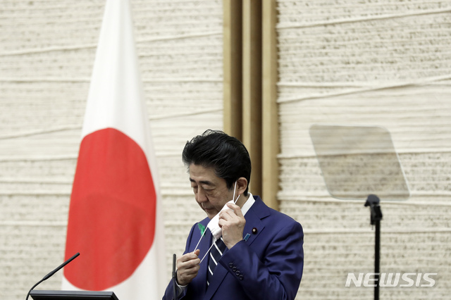 [도쿄=AP/뉴시스]아베 신조(安倍晋三) 일본 총리가 지난 17일 도쿄 총리공관에서 기자회견을 시작하기 위해 마스크를 벗고 있다. 2020.4.19