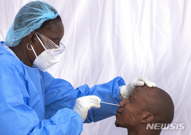 [요하네스버그=AP/뉴시스]19일(현지시간) 남아프리카공화국 요하네스버그의 템비사 마을에서 신종 코로나바이러스 감염증(코로나19) 예방을 위해 마스크를 쓴 한 의료인이 한 남성의 검체를 채취하고 있다.2020.05.20. 