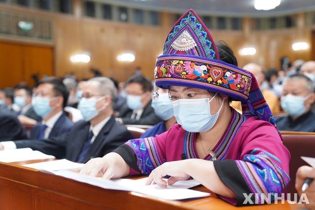 [베이징=신화/뉴시스] 신종 코로나 바이러스 감염증(코로나 19)로 연기됐던 중국 정책자문 회의인 전국인민정치협상회의(정협)가 21일 오후 베이징 인민대회당에서 개막된 가운데, 마스크를 쓴 소수족 출신의 한 위원이 문건을 읽고 있다. 2020.05.21 