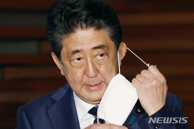 [도쿄=AP/뉴시스]아베 신조 일본 총리가 21일 기자회견에서 마스크를 벗고 있다. 일본 정부는 이날 3개 지역에 대해 긴급사태 선언 추가 해제를 발표했다. 도쿄 등 5개 지역에 대해서는 오는 25일 다시 검토하겠다고 밝혔다. 2020.05.22.