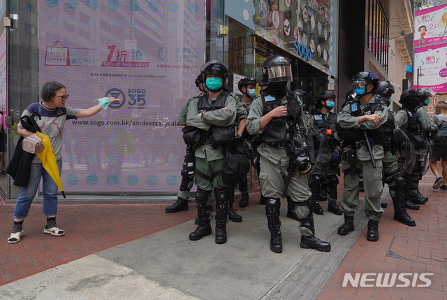 [홍콩=AP/뉴시스]27일 홍콩 중심부에서 한 여성이 시위 진압 경찰이 경비중인 거리를 건너려 하고 있다. 중국 전국인민대표대회(전인대)가 처벌 대상을 대폭 확대하는 홍콩 국가보안법 수정안을 추진하는 가운데 홍콩 시위대는 입법부 청사 밖에서 이에 반대하는 시위를 벌이고 있다. 2020.05.27.