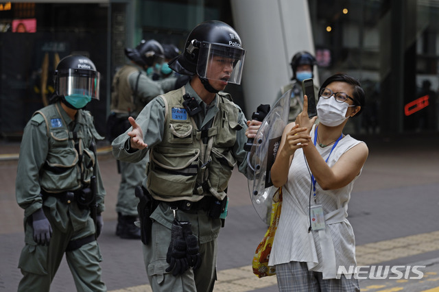 [홍콩=AP/뉴시스]27일(현지시간) 홍콩 몽콕에서 한 시위진압 경찰관이 시위대를 연행하는 경찰의 모습을 찍고 있는 한 여성을 제지하고 있다. 마이크 폼페이오 미 국무장관은 "홍콩이 더는 중국으로부터 자치권을 갖고 있지 않다"라고 판단하며 이를 의회에 보고했다고 밝혔다. 이는 중국 정부가 전국인민대표대회를 통해 홍콩 국가보안법(보안법)을 통과시킬 경우 미국이 홍콩에 부여해온 특별지위 일부를 박탈하겠다는 경고로 풀이되고 있다. 2020.05.28.