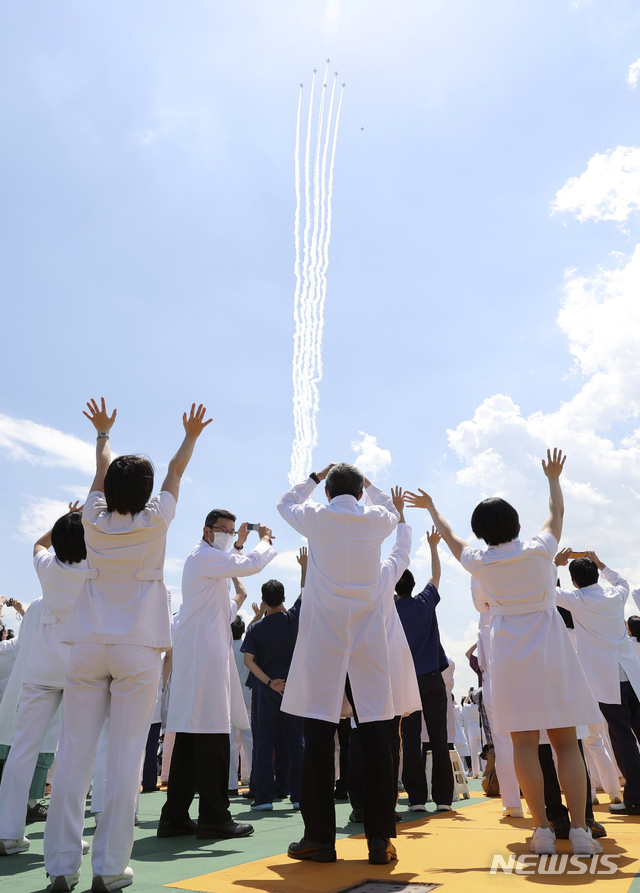  [도쿄=AP/뉴시스]일본 항공자위대 곡예비행팀 '블루 임펄스'가 29일 도쿄에서 신종 코로나바이러스 감염증(코로나19)과 싸우는 의료진을 위한 격려 비행을 하는 가운데 의료진이 이를 보며 환호하고 있다. 2020.05.29. 