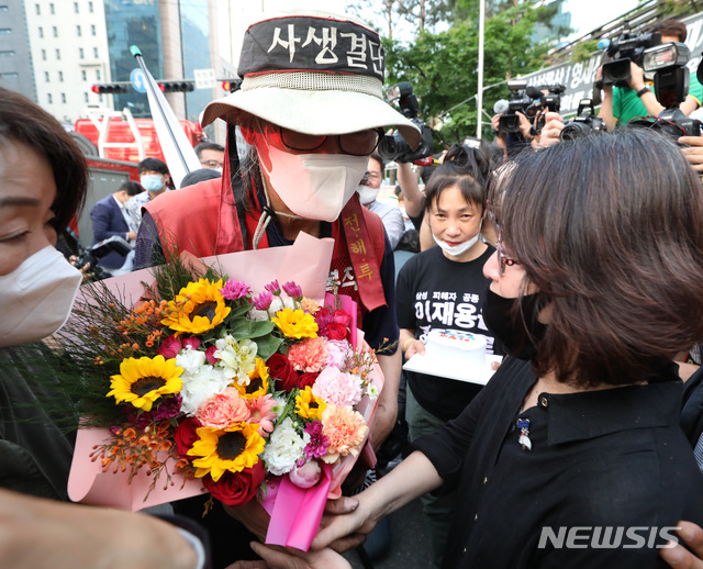 [서울=뉴시스] 전진환 기자 = 삼성항공에 노조를 만들려다 해고돼 복직을 위한 고공농성을 벌여온 김용희씨가 29일 오후 농성을 하던 강남역 사거리 철탑에서 내려와 꽃다발을 받고 있다. 2020.05.29.   amin2@newsis.com 