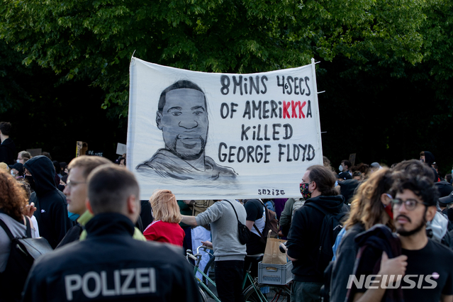 [베를린=AP/뉴시스] 미국 미네소타주 미니애폴리스에서 비무장 상태의 흑인 남성 조지 플로이드(46)가 백인 경찰 데릭 쇼빈(44)의 가혹 행위로 숨진 사건에 항의하는 시위가 독일 베를린에서도 벌어졌다. 사진은 30일(현지시간) 시위 참가자들이 사망한 플로이드의 얼굴을 그린 플래카드를 들고 주베를린 미 대사관 앞을 행진하는 모습. 2020.6.1.