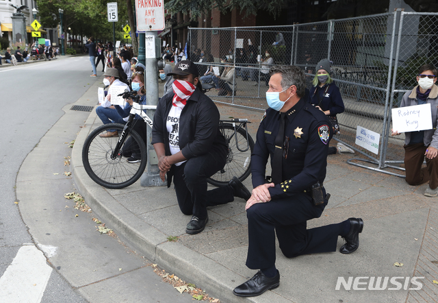 [산타크루즈=AP/뉴시스] 미 캘리포니아주 산타크루즈의 앤디 밀스(오른쪽)경찰서장이 저스틴 커밍스(가운데) 산타크루즈 시장과 함께 한 쪽 무릎을 꿇고 있다. 이들은 인종차별 반대 시위를 진압하는 대신 시민들과 뜻을 함께 하겠다고 밝혔다. 2020.6.1.