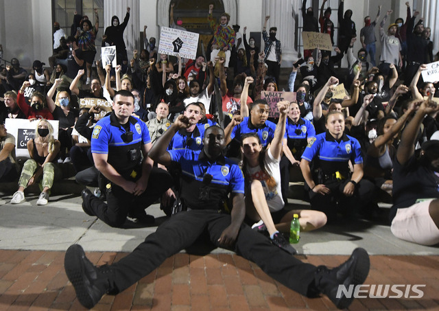 [윌밍턴=AP/뉴시스] 미국 노스캐롤라이나주 윌밍턴 경찰서 소속 경관들이 1일(현지시간) 윌밍턴 시청 앞에서 열린 조지 플로이드 사망 항의 시위에 참석해 한쪽 무릎을 꿇은채 시위대와 함께 구호를 외치고 있다.