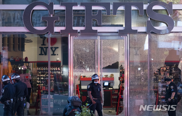 [뉴욕=AP/뉴시스]2일(현지시간) 미국 뉴욕에서 경찰이 시위로 창문이 깨진 상점 앞에 서 있다. 백인 경찰의 가혹행위로 흑인 조지 플로이드가 사망한 사건을 규탄하는 시위가 8일째에 접어들었다. 2020.06.02. 