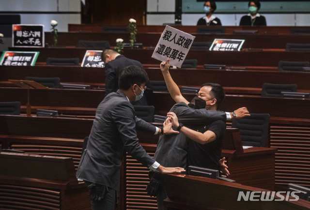 [홍콩=AP/뉴시스] 홍콩 민주파 의원이 4일 국가법 제정 논의가 진행되고 있는 입법회에서 "수만년 냄새나는 살인정권"이라고 쓴 팻말을 들어올리며 시위를 벌이다가 저지 당하고 있다. 홍콩 입법회는 이날 국가 모욕을 처벌하는 법안을 통과시킬 예정이다. 2020.06.04 
