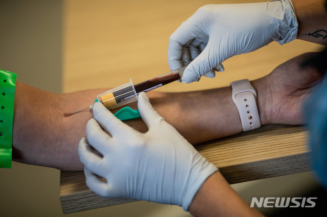 A paramedic, right, takes a blood sample from a front line ambulance worker during an antibody testing program at the Hollymore Ambulance Hub, in Birmingham, England, on Friday, June 5, 2020. Making antibody tests widely available may help Britain lift its lockdown restrictions, because they show who has already had the COVID-19 and might have a degree of immunity from coronavirus. (Simon Dawson/Pool via AP)
