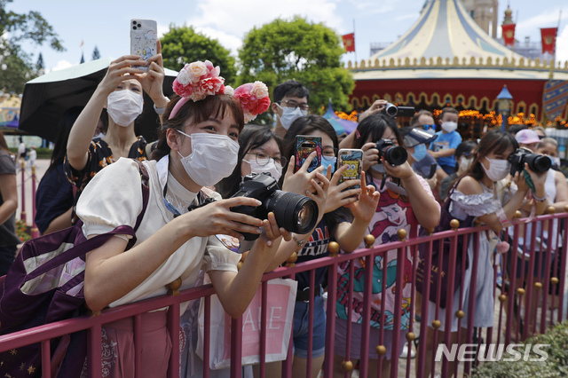 [홍콩=AP/뉴시스]18일(현지시간) 신종 코로나바이러스 감염증(코로나19) 사태로 문을 닫았다가 재개장한 홍콩 디즈니랜드에서 방문객들이 마스크를 쓴 채 사진을 찍고 있다. 2020.07.01. 