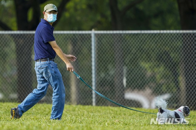 [리처드슨=AP/뉴시스]지난 2일 텍사스 리처드슨에서 한 남성이 마스크를 착용한 채 강아지를 산책시키고 있다. 통계 사이트 월드오미터에 따르면 6일(현지시간) 기준 미국 내 신종 코로나바이러스 감염증(코로나19) 누적 확진자는 300만명을 넘어섰다. 2020.07.07.