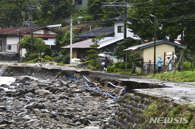  [다카야마=AP/뉴시스]10일 일본 기후현 다카야마에서 주민들이 호우로 유실된 도로를 걷고 있다. 일본 일부 지역에서 실종자 수색 작업과 복구 작업이 이어지는 가운데 관계 당국은 이번 주말 더 많은 비가 내릴 것에 대비하고 있다. 2020.07.10. 