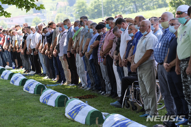 [스레브레니차(보스니아-헤르체고비나)=AP/뉴시스]보스니아 스레브레니차 인근 포토카리에서 11일 열린 스레브레니차 학살 25주년 기념식에서 참석자들이 희생자들의 관 앞에서 기도하고 있다. 2020.7.12