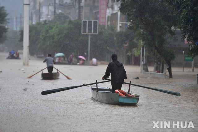 [광시=AP/뉴시스]12일 중국에서 홍수가 계속되는 가운데 광시 좡족 자치구에서 물로 가득찬 거리를 사람들이 배를 타고 건너고 있다. 2020.07.12.