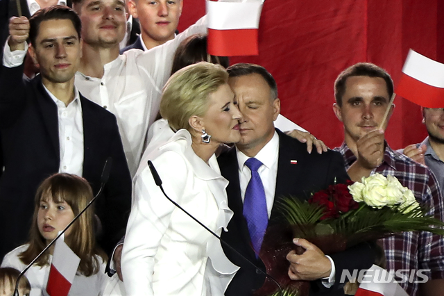 [풀투스크=AP/뉴시스]안제이 두다(가운데) 폴란드 대통령이 12일(현지시간) 폴란드 풀투스크에서 부인 안나 코모로프스카와 포옹하고 있다. 그는 이날 치러진 대선 결선투표 출구조사 결과 라파우 트샤스코프스키 바르샤바 시장에 지지율에서 앞서는 것으로 나타났다. 2020.07.12.