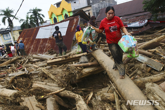 [마삼바(인도네시아)=AP/뉴시스]15일(현지시간) 인도네시아 술라웨시슬라탄주에 국지성 집중호우가 내려 홍수가 발생한 마삼바 마을 주민들이 잔해 사이를 걷고 있다. 인도네시아 술라웨시슬라탄주에 지난 12일부터 내린 폭우로 강물 범람, 진흙 사태 등이 일어나 약 5천 가구가 수해를 입고 최소 15명이 숨졌다고 현지 관계자가 밝혔다. 2020.07.15.