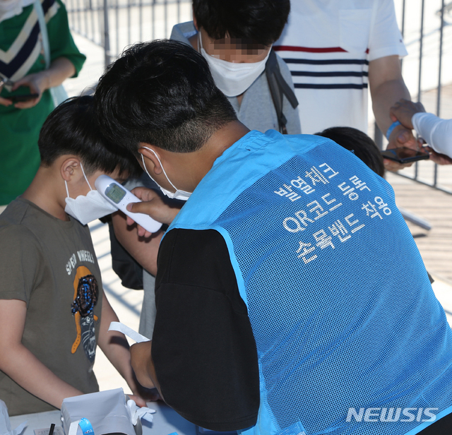 [강릉=뉴시스] 김경목 기자 = 해수욕장 개장 첫날인 17일 오후 강릉시 관계자가 강원 강릉시 안현동 경포해수욕장 중앙통로 출입구에서 어린이의 발열 여부를 확인하고 있다. 강릉시는 신종 코로나바이러스 감염증(코로나19) 확산 예방을 위해 해수욕장을 출입하는 피서객을 대상으로 QR코드 전자출입명부 등록, 발열 상태 확인, 파란색 손목밴드 제공 절차를 운영 기간 동안 진행한다. 2020.07.17. photo31＠newsis.com