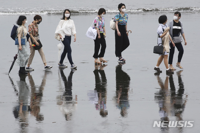 [가나가와=AP/뉴시스]일본이 '바다의 날'로 휴일을 맞았던 지난 23일 도쿄 인근 가나가와현 후지사와의 해변에서 사람들이 신종 코로나바이러스 감염증(코로나19) 예방을 위해 마스크를 쓰고 걷고 있다. 2020.07.24. 