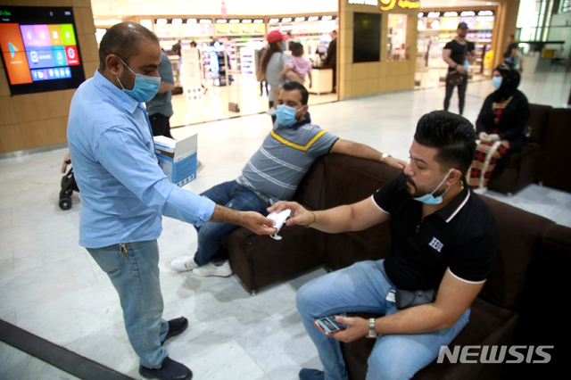 [바그다드=AP/뉴시스]지난 달 23일(현지시간) 이라크 바그다드 국제공항에서 신종 코로나바이러스 감염증(코로나19) 예방을 위해 사람들에게 마스크를 배포하고 있다. 2020.08.02.