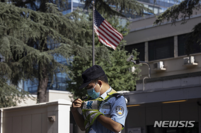 A Chinese police officer adjusts his vest near the U.S. flag flying in the United States Consulate in Chengdu in southwest China&#039;s Sichuan province on Sunday, July 26, 2020. China ordered the United States on Friday to close its consulate in the western city of Chengdu, ratcheting up a diplomatic conflict at a time when relations have sunk to their lowest level in decades. (AP Photo/Ng Han Guan)