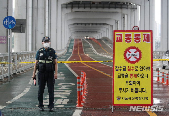 [서울=뉴시스]김병문 기자 = 중부지방에 집중호우가 내리는 2일 오후 서울 용산구 잠수교에서 교통경찰이 보행자와 자전거 통행을 제한하고 있다. 2020.08.02.  dadazon@newsis.com 