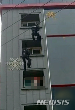 [부산=뉴시스] 경찰특공대가 부산의 한 모텔 창문틀에 걸터앉아 투신 소동을 벌이던 30대를 구조하고 있다. (사진=부산경찰청 제공)