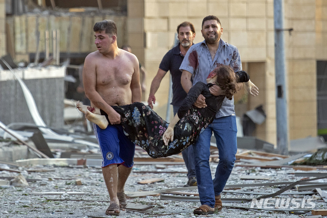 [베이루트=AP/뉴시스]4일(현지시간) 레바논 수도 베이루트 항구에서 대규모 폭발사고가 일어나 시민들이 한 부상 여성을 옮기고 있다. 폭발로 거대한 버섯구름이 떠 오르고 항구 상당 부분이 파괴됐으며 시내 곳곳의 건물이 부서지면서 유리와 문짝 등 파편으로 많은 부상자가 생겼다. 하마드 하산 레바논 보건장관은 최소 50명이 숨지고 약 2800명이 다쳤으며 사망자는 더 늘어날 전망이라고 밝혔다. 2020.08.05. 