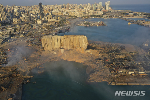 [베이루트=AP/뉴시스] 레바논 베이루트 항구에서 폭발사건이 발생한 다음 날인 5일(현지시간)에도 연기가 피어오르고 있다. 초대형 폭발로 파괴된 창고 건물의 일부가 서있고, 그 앞의 땅이 분화구처럼 함몰돼있는 것이 보인다. 2020.08.06 