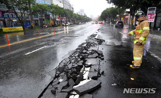 [광주=뉴시스] 류형근 기자 = 많은 비가 내린 7일 오후 2시께 광주 서구 상무중학교 앞 도로가 파손돼 차량 통행이 제한되고 있다. 2020.08.07. hgryu77@newsis.com