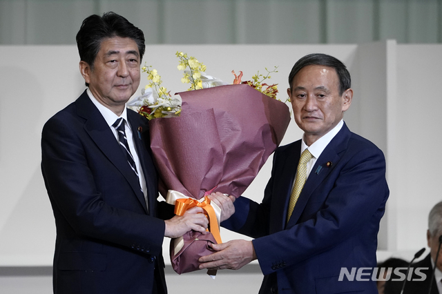 [도쿄=AP/뉴시스]아베 신조(왼쪽) 일본 총리가 지난 14일 도쿄의 한 호텔에서 열린 자민당 총재 선거에서 총재로 선출된 스가 요시히데 관방장관에게 꽃다발을 건네며 축하하고 있다. 스가 관방장관은 이날 열린 총재 선거에서 총재로 선출돼 사실상 새 총리로 확정됐다. 2020.09.14. 