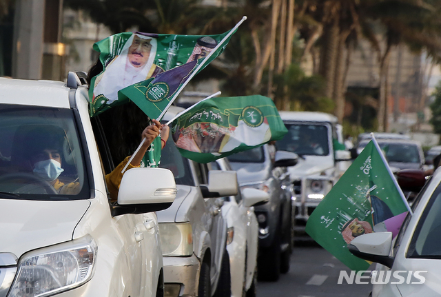 [제다=AP/뉴시스] 9월23일(현지시간) 사우디아라비아 제다에서 열린 사우디 국립기념일 행사의 모습. 사우디 국기에 사우디 왕족들의 사진이 담겨 있다. 2020.10.29.