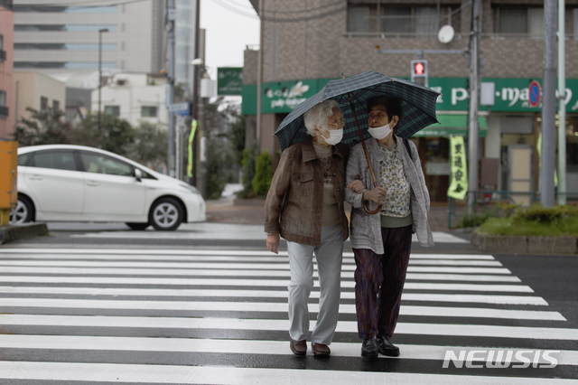 [도쿄=AP/뉴시스]지난 24일 일본 도쿄의 한 횡단보도를 마스크를 쓴 시민들이 우산을 쓰고 건너가고 있다. 2020.09.25.