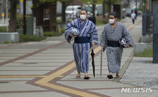 [도쿄=AP/뉴시스]24일 일본 도쿄 료고쿠 국기관 앞을 마스크를 쓴 스모 선수들이 걷고 있다. 2020.09.24.