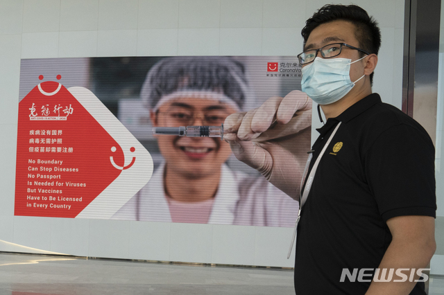 [베이징=AP/뉴시스] 24일(현지시간) 중국 제약사 시노백의 베이징 공장에서 한 직원이 신종 코로나바이러스 감염증(코로나19) 백신 광고판 앞에 서 있다. 2020.09.27. 