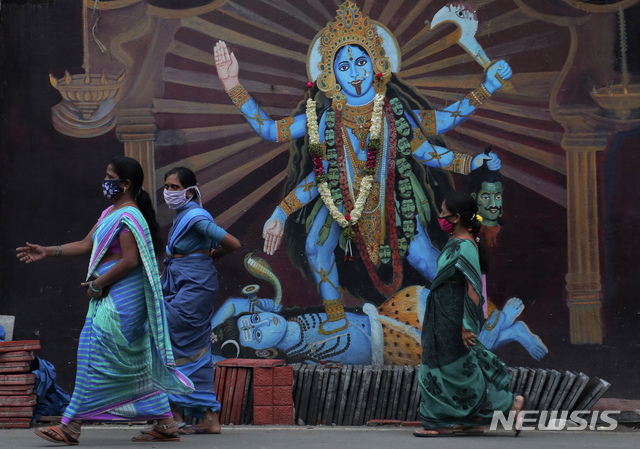 [하이데라바드=AP/뉴시스] 11일 인도에서 마스크를 쓴 여성들이 사원 앞 힌두 여신 두르가 상을 지나고 있다. 인도는 이날 코로나 19 확진자가 하루 8만 명 가까이 추가돼 총 705만 명을 넘어섰다. 미국을 66만 명 차로 뒤쫓고 있다. 