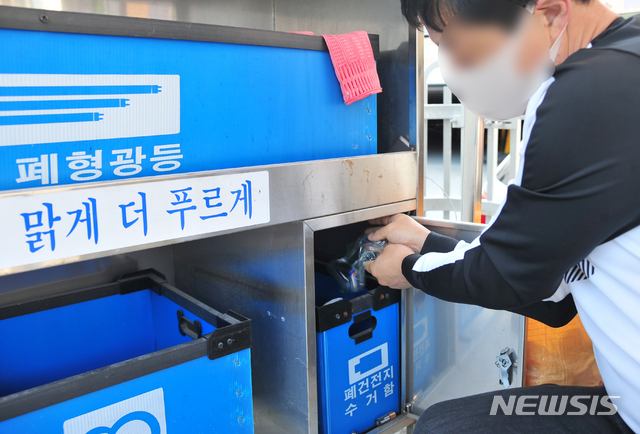 [광주=뉴시스] 김혜인 기자 = 주민이 광주 남구 주월동 모 아파트 분리수거장에서 폐건전지를 수거함에 버리고 있다. 2020.10.24. hyein0342@newsis.com