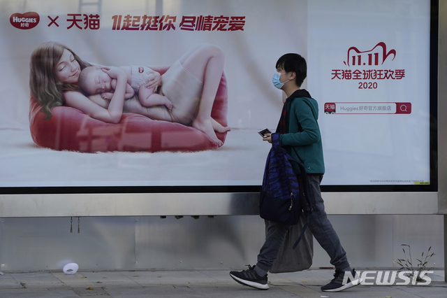 [베이징=AP/뉴시스]지난 10월28일 중국 베이징에서 코로나19 확산 방지를 위해 마스크를 쓴 한 남성이 광군제(11월11일) 할인 판매 광고판 앞을 지나고 있다. 2020.11.10.