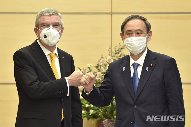 [도쿄=AP/뉴시스]일본을 방문한 토마스 바흐 국제올림픽위원회(IOC) 위원장(왼쪽)이 지난해 11월16일 오전 스가 요시히데 일본 총리(오른쪽)와 도쿄 총리 관저에서 만나 회담 전 주먹 인사를 나누고 있다. 2021.01.21.