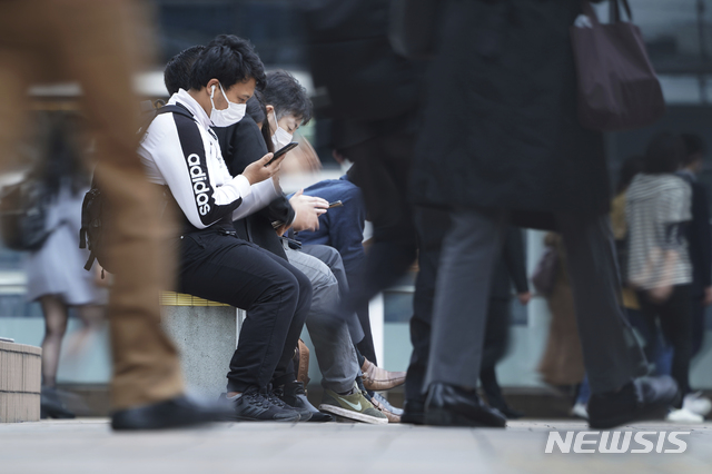 [도쿄=AP/뉴시스]지난 20일 일본 도쿄에서 출근 시간에 신종 코로나바이러스 감염증(코로나19) 확산 방지를 위해 마스크를 쓴 사람들이 한 지하철역 통로 밖 의자에 앉아 있다. 2020.11.21.