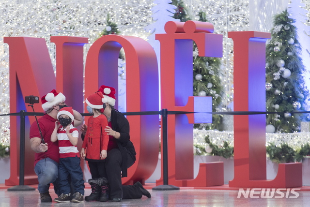 [몬트리올=AP/뉴시스]캐나다와 전 세계에 코로나19 대유행이 계속되는 가운데 22일(현지시간) 캐나다 몬트리올에서 마스크를 쓴 한 가족이 크리스마스 장식폼 앞에서 기념사진을 찍고 있다. 2020.11.23.