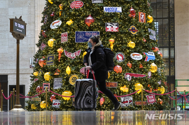 [시카고=AP/뉴시스]25일(현지시간) 마스크를 쓴 여행객이 미국 시카고 유니온역의 크리스마스 트리 앞을 지나고 있다. 2020.11.26.
