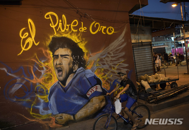 [리우데자네이루=AP/뉴시스]25일(현지시간) 브라질 리우데자네이루에서 한 소년이 자전거를 타고 디에고 마라도나의 벽화 앞을 지나고 있다. 1986년 아르헨티나를 월드컵 우승으로 이끈 아르헨티나 축구 영웅 디에고 마라도나가 25일 부에노스아이레스 자택에서 심장마비로 타계했다. 향년 60세. 2020.11.26. 