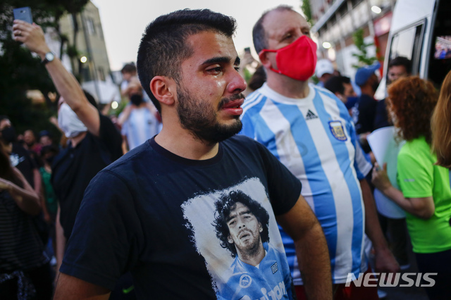 [부에노스아이레스=AP/뉴시스]25일(현지시간) 아르헨티나 부에노스아이레스의 아르헨티노스 주니어스 경기장 밖에서 디에고 마라도나의 얼굴이 담긴 셔츠를 입은 한 남성이 마라도나의 죽음에 눈물짓고 있다. 1986년 아르헨티나를 월드컵 우승으로 이끈  아르헨티나 축구 영웅 디에고 마라도나가 25일 부에노스아이레스 자택에서 심장마비로 타계했다. 향년 60세. 2020.11.26. 